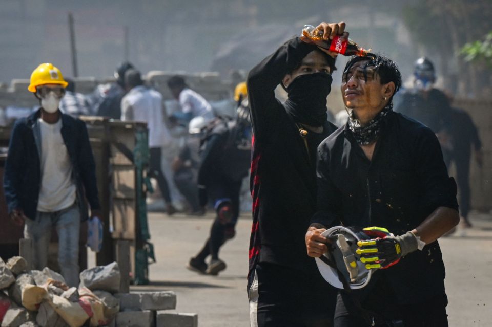 A protester pours Coca-Cola on the face of a comrade to diminish the effects of tear gas