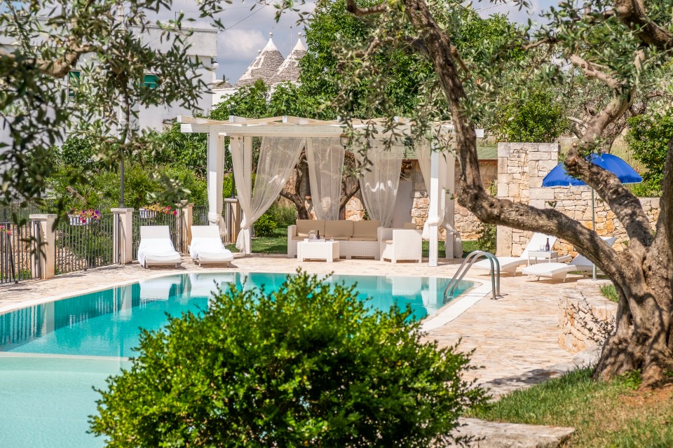 a swimming pool with a pergola and chairs around it