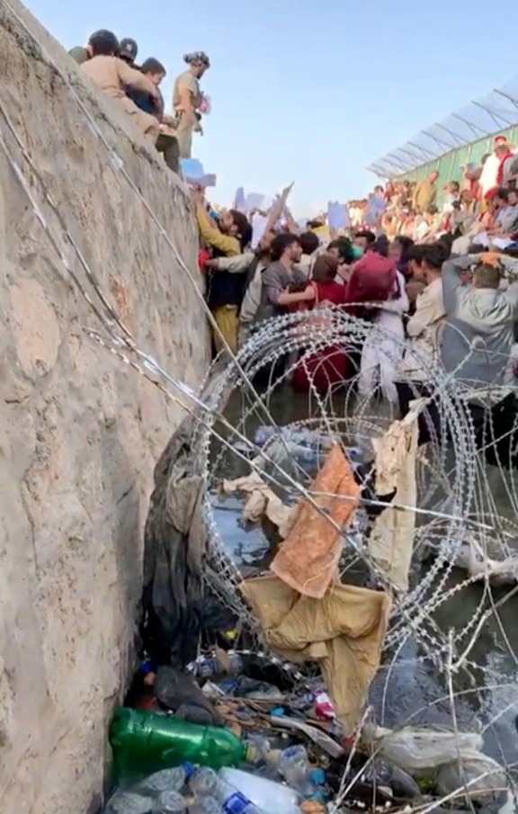 People pictured wading through the sewage to give documents to troops on the other side
