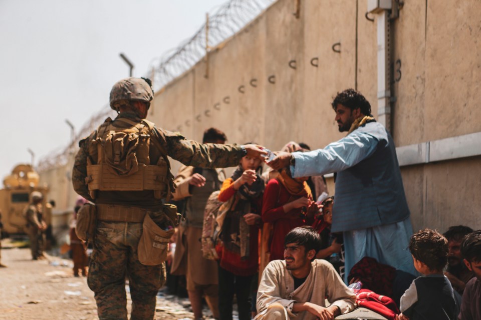 A soldier hands water to Afghans as they wait as Kabul airport