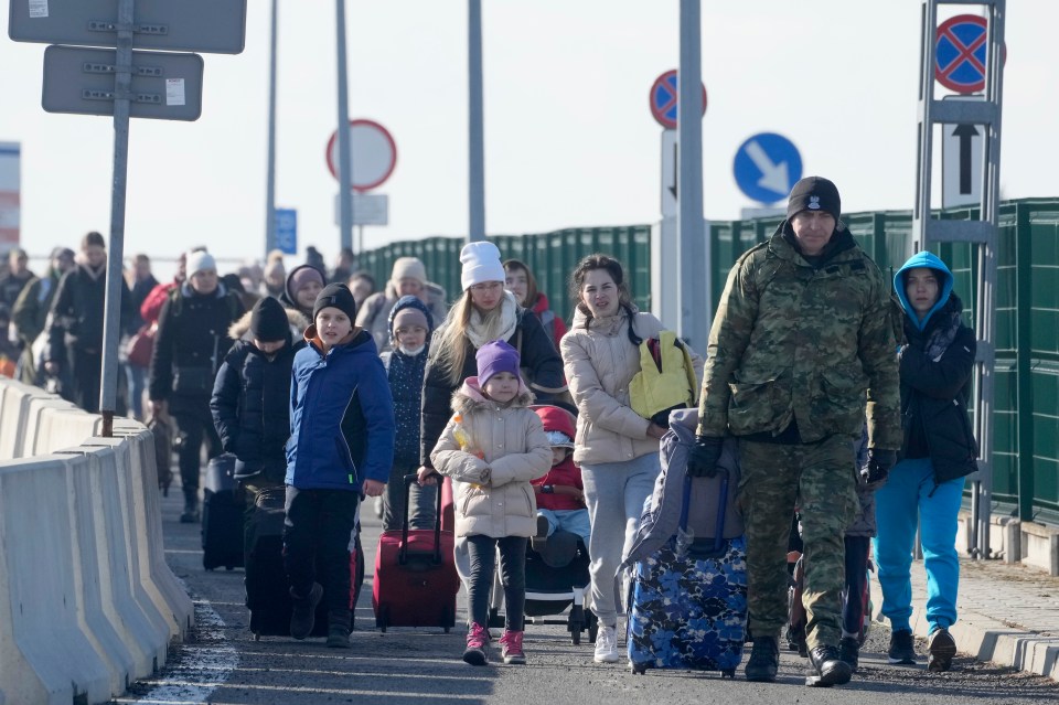 A Polish border guard assists Ukrainian refugees as they arrive at the Korczowa crossing