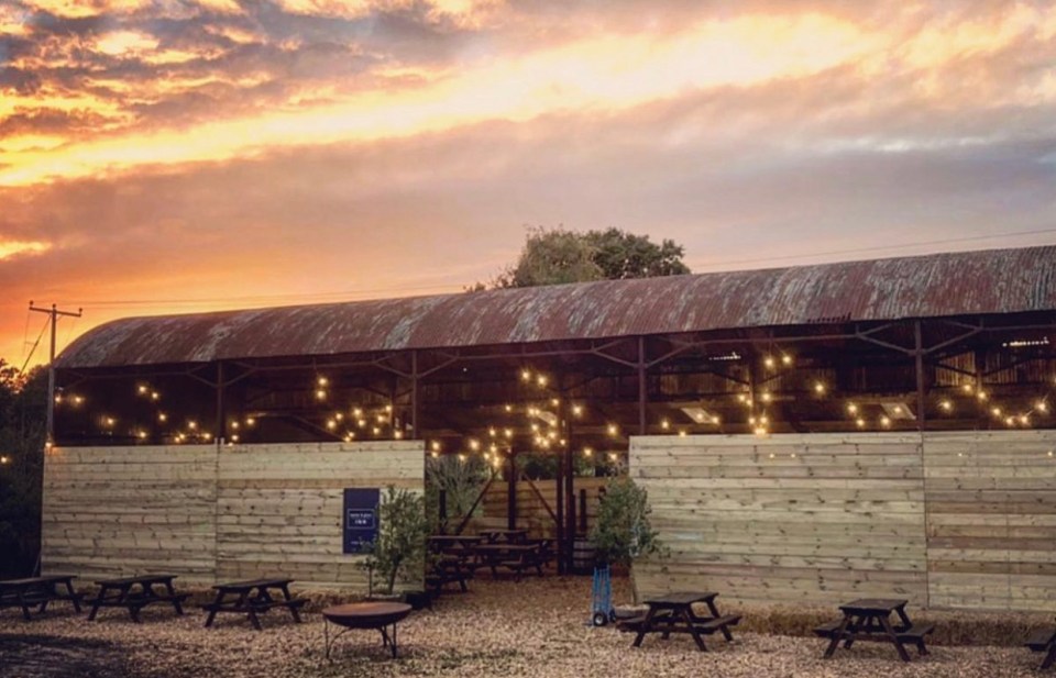 The open-sided barn has a massive fire pit, delivers draft beer and serves burgers and pizzas