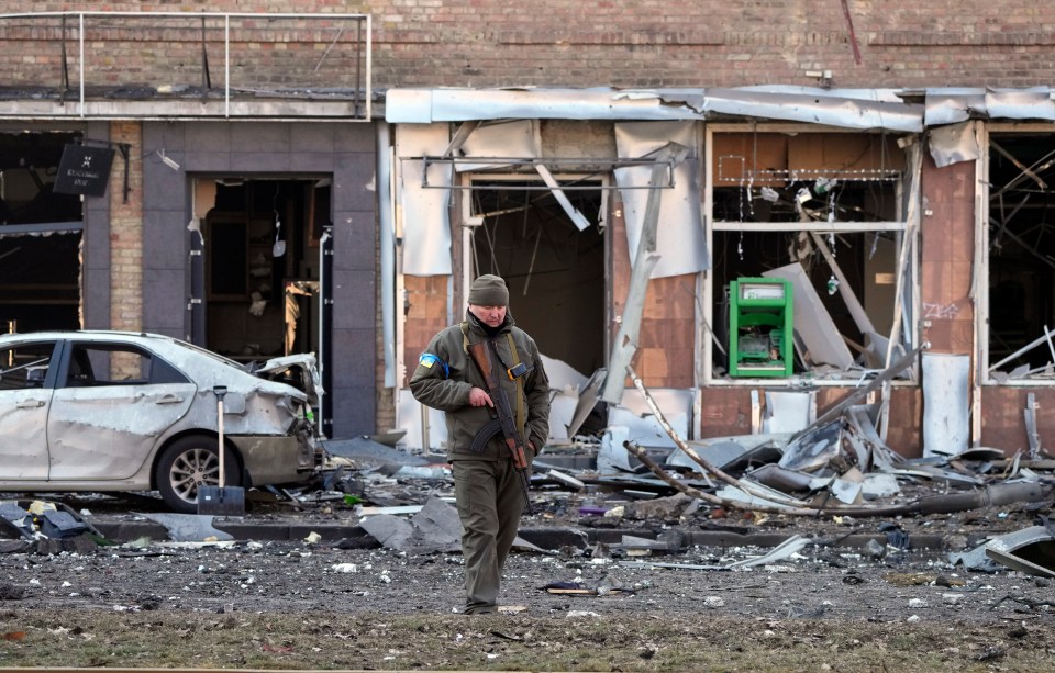 Ukrainian soldier passes at a destroyed building after a Russian bombing attack in Kyiv