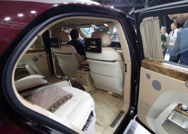 a man is sitting in the back seat of a car at a car show .