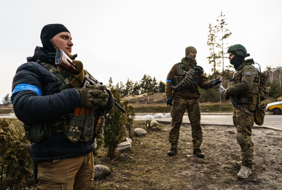 Ukrainian soldiers stand ready at a checkpoint in Irpin
