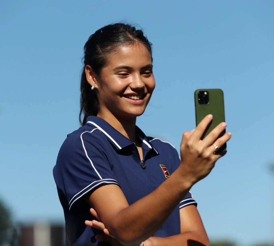 a woman taking a selfie with her phone while wearing a tennis shirt
