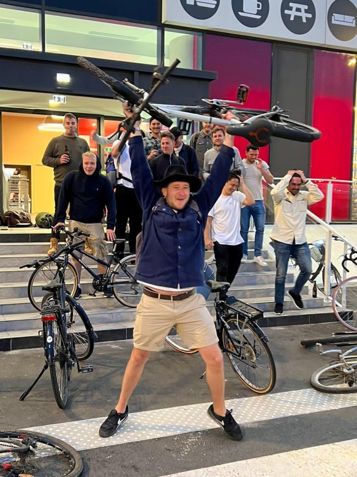 Alex Sisan holds his bike aloft after his stag-do party's epic 230-mile mission to get home from Amsterdam