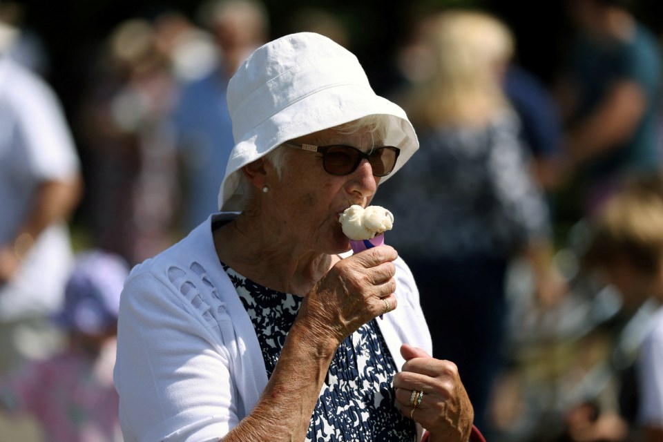 A woman enjoys an ice cream during hot weather at the Kent County Show in Maidstone