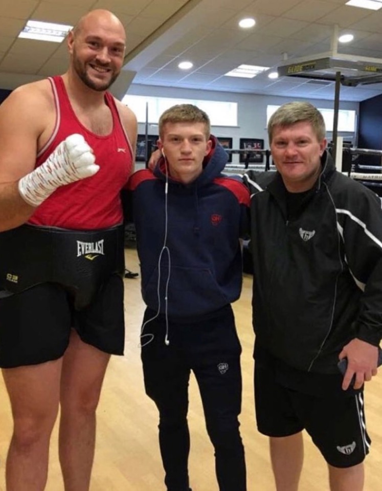Three men posing for a photo, one is a large boxer.
