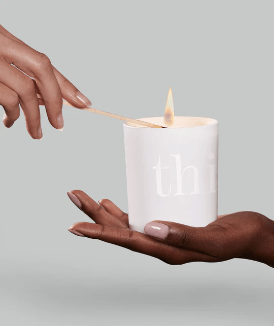 A hand lighting a white candle.
