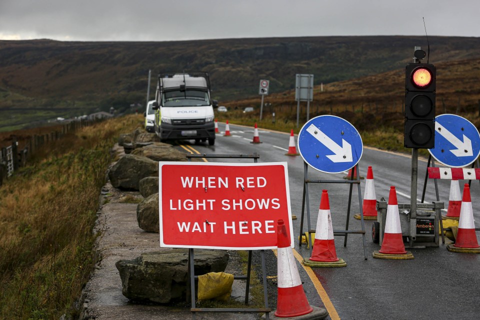 Temporary traffic lights have been installed on a stretch of road coned off for police vehicles