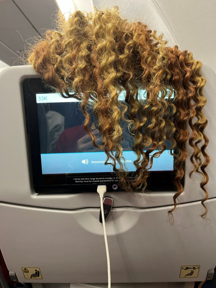 The woman in front was draping her long hair over the back of the seat