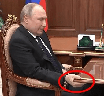 Vladimir Putin sitting at a large desk.