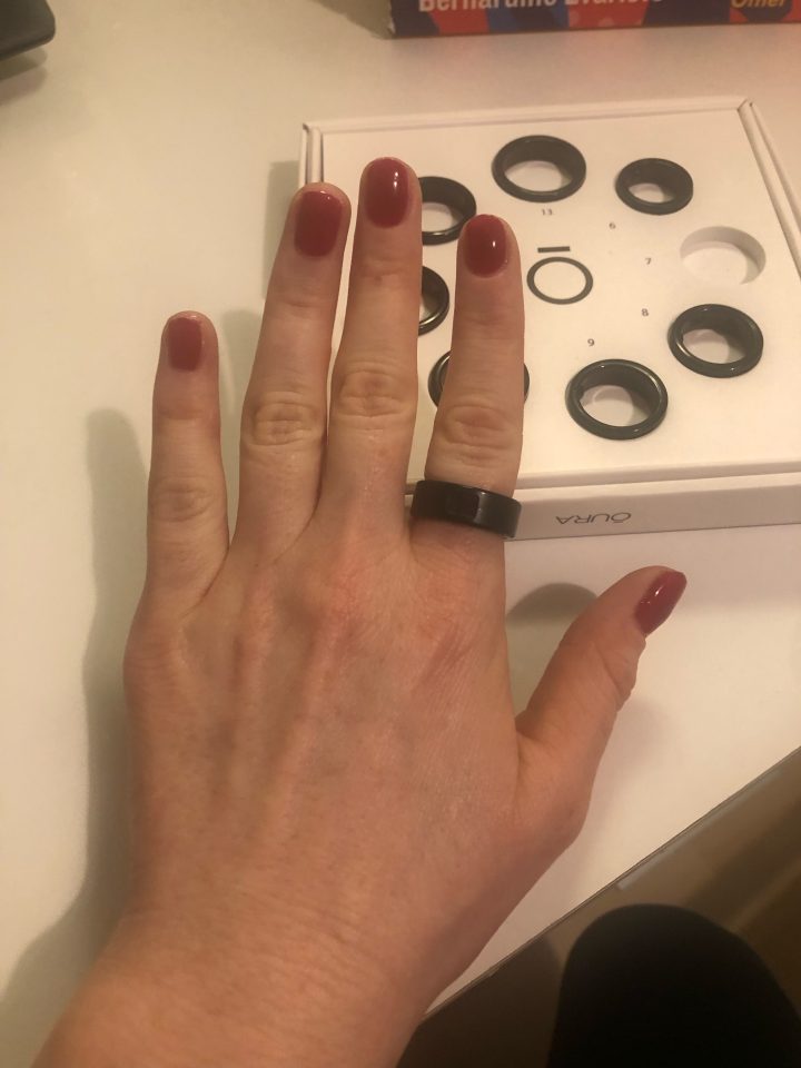 a woman 's hand with red nails is wearing a black aura ring