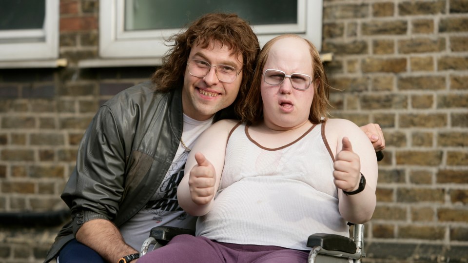 a man sitting next to a man in a wheelchair giving a thumbs up