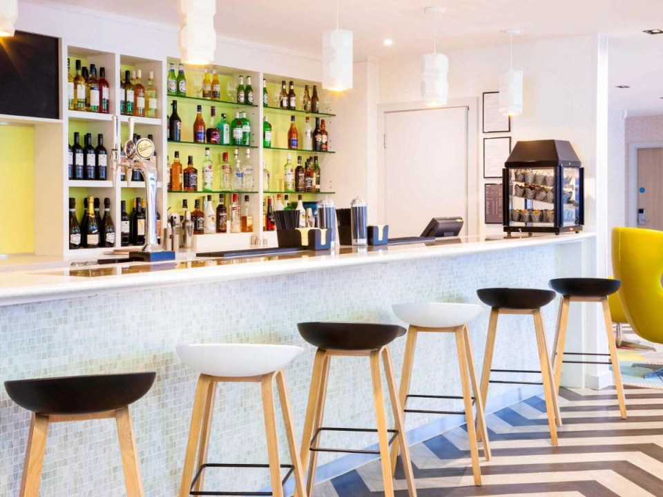 Hotel bar with stools and liquor shelves.