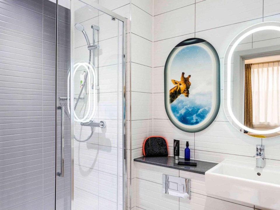 Hotel bathroom with shower and giraffe artwork.