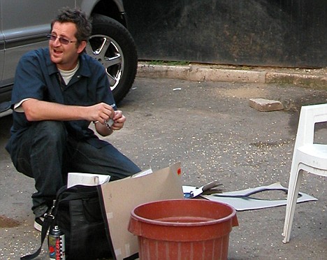 a man in a blue shirt is kneeling down next to a bucket of water