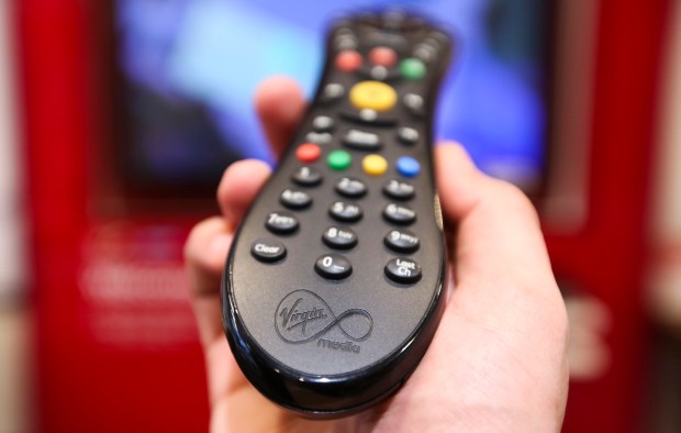 A hand holding a Virgin Media remote control.