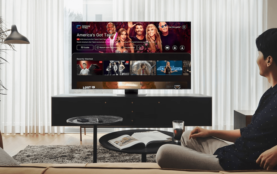 a man sits on a couch watching america 's got talent