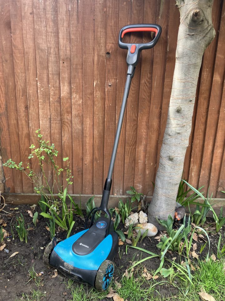 A blue and black robotic lawnmower in a garden.