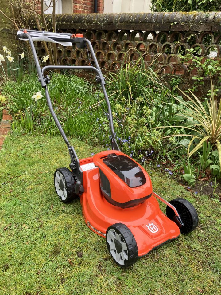 Orange Husqvarna lawnmower on a grass lawn.