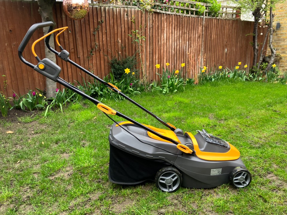 A grey and yellow lawnmower on a grass lawn.