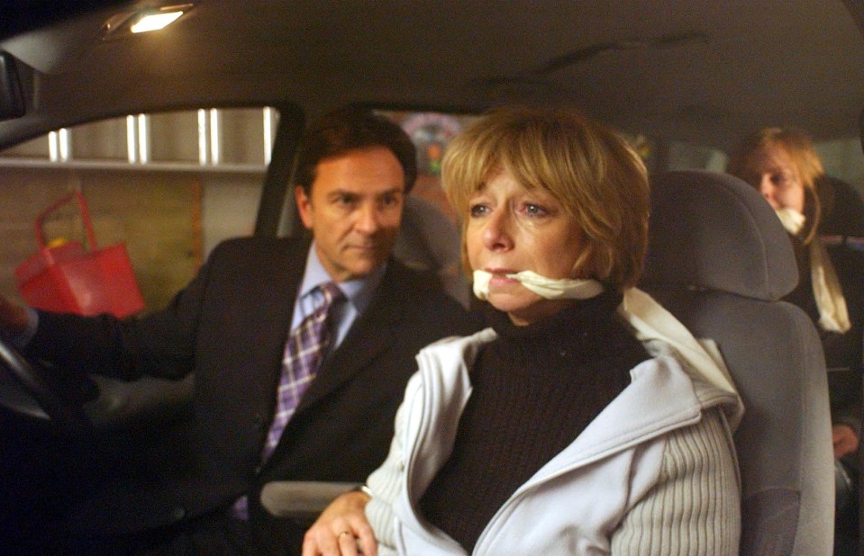 Still image from Coronation Street showing Gail Hillman bound and gagged in the back of a car, with Richard Hillman in the driver's seat.