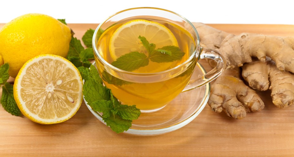 a cup of tea with lemon and mint next to ginger