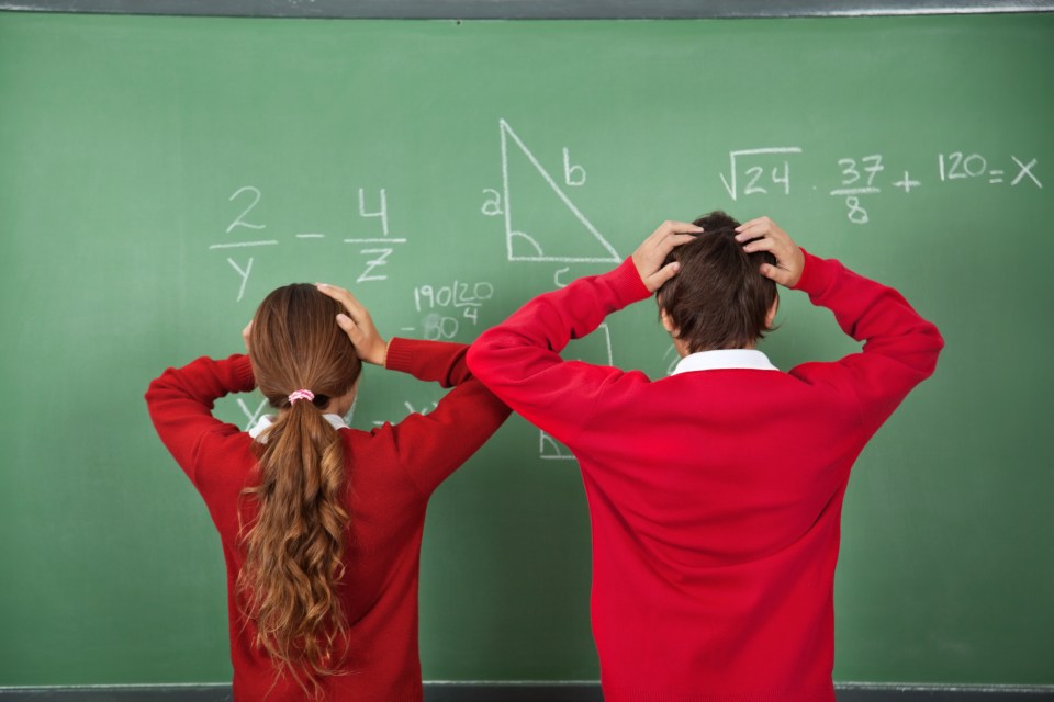 Rear view of confused schoolchildren standing against board in classroom; Shutterstock ID 158645414; purchase_order: -; job: -; client: -; other: -