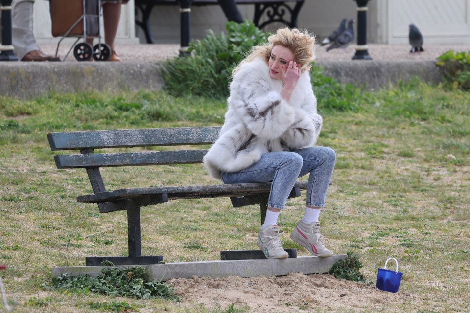 Sophie wrapped up in a huge white fur coat and acid wash jeans for the scenes