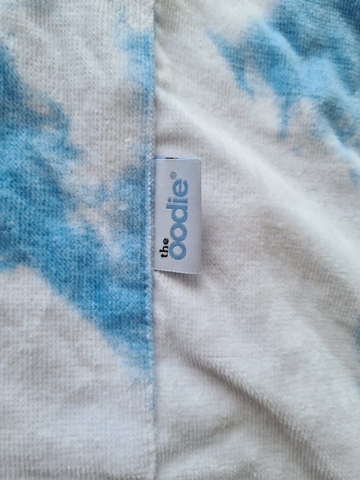 The Oodie label on a blue and white tie-dye blanket.