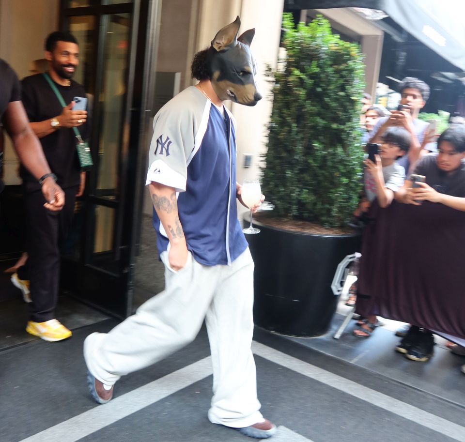 Drake wore a rubber rottweiler headpiece while leaving his hotel in New York on Thursday