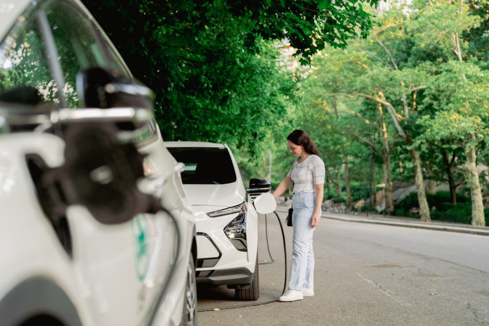 woman charging electric car in park in new york
