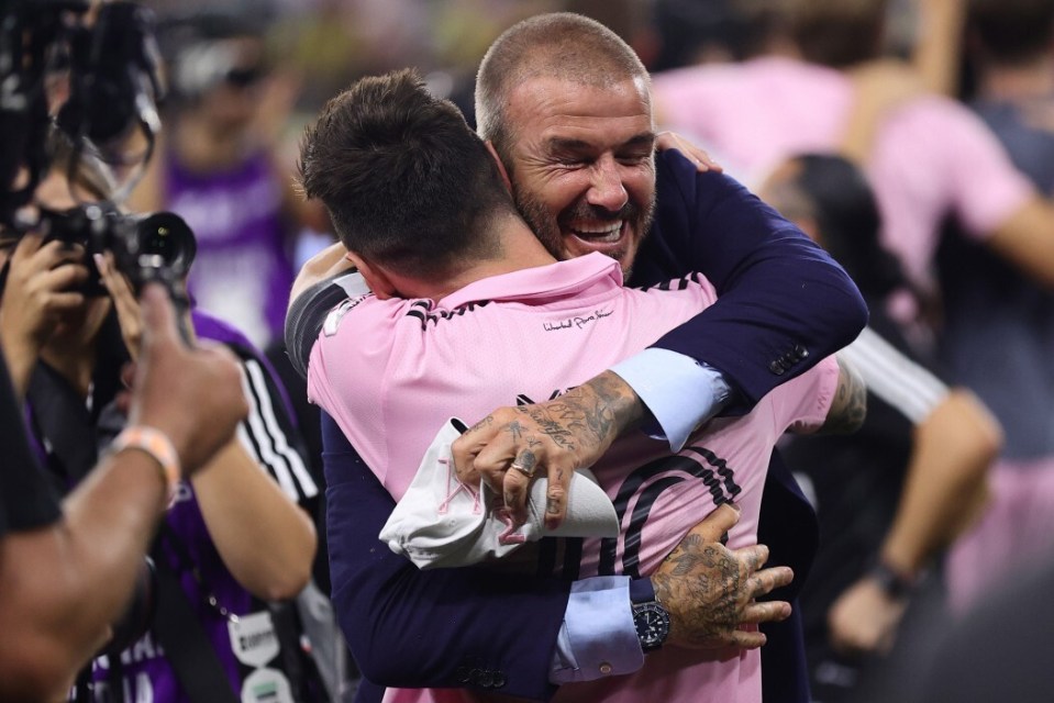 a man wearing a pink shirt that says ' united states ' on it is hugging another man