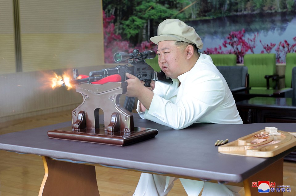 Dictator Kim Jong-un was seen test firing a weapon during a tour of a factory