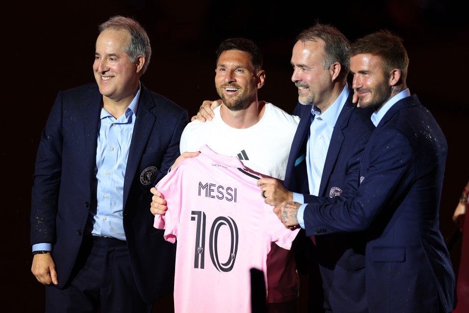 a man holding a pink shirt that says messi 10