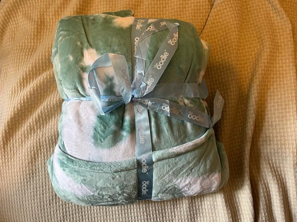 a green and white tie dye blanket with a blue ribbon that says ' doodle ' on it