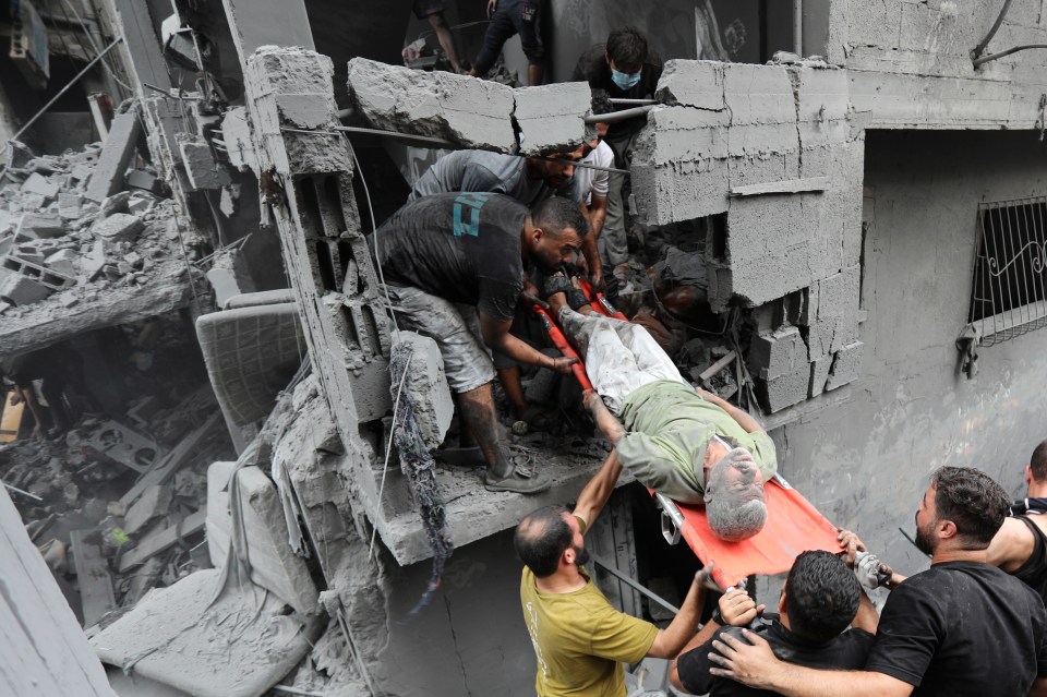 Palestinians carry an injured man out of the destruction following Israeli airstrikes
