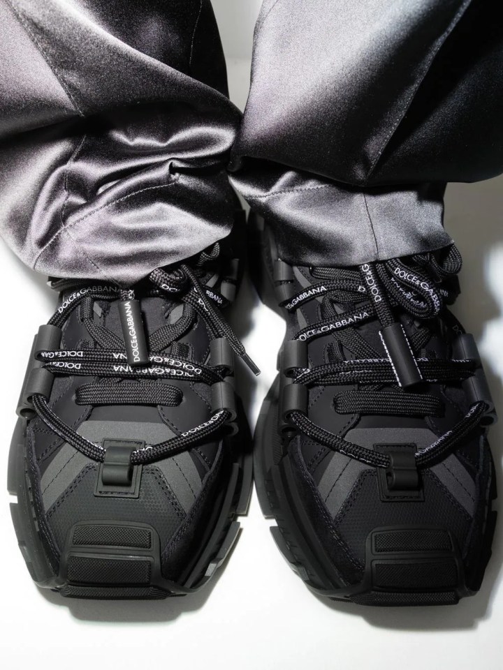 a pair of black dolce & gabbana sneakers on a person 's feet