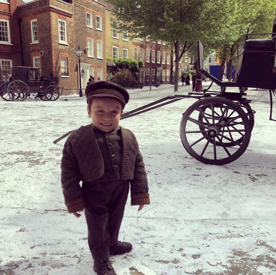 a little boy standing in front of a horse drawn carriage