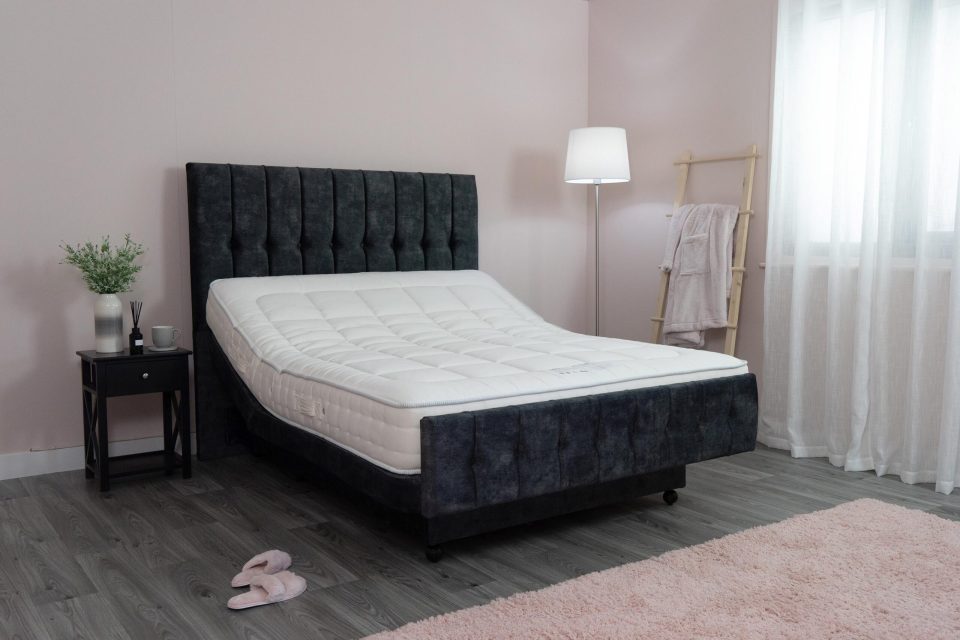 Adjustable bed with dark headboard and white mattress.