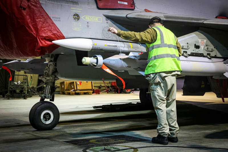 An RAF weapons experts prepares a jet with missiles for the strikes on Monday