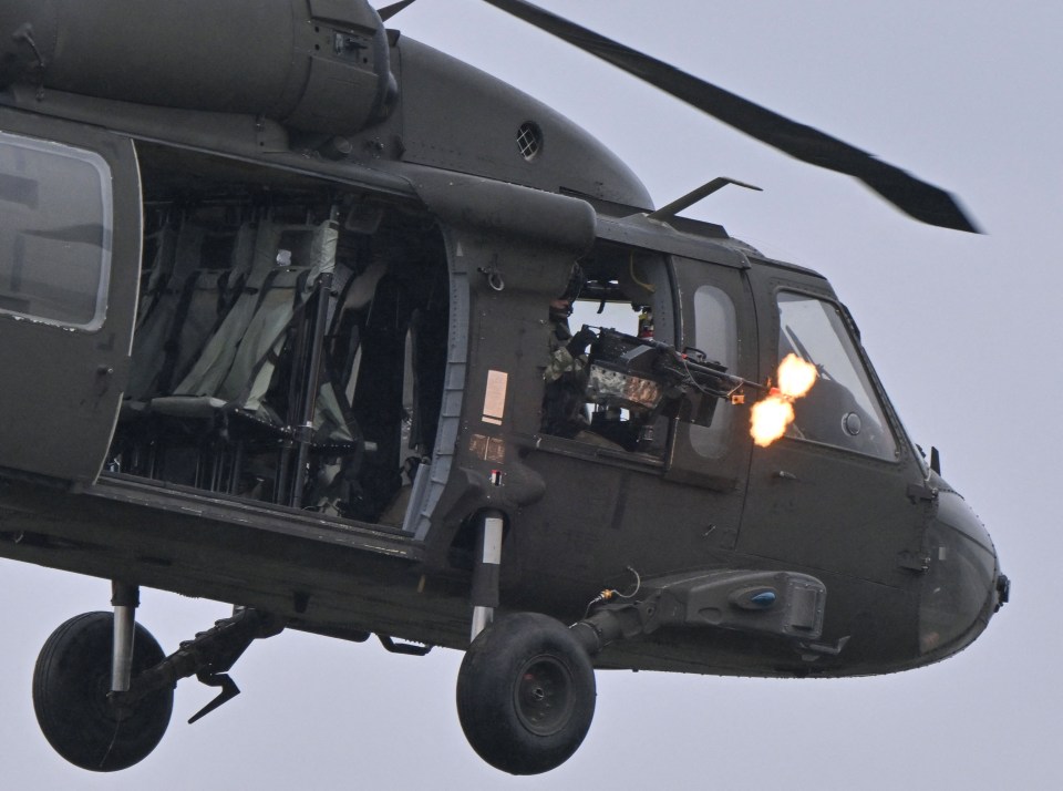 A serviceman shoots from a Black Hawk helicopter during a demonstration as part of the rotation of US troops