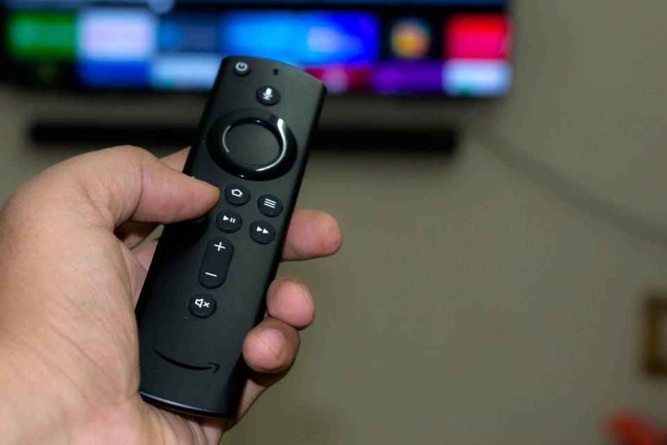 Hand holding an Amazon Fire Stick TV remote.