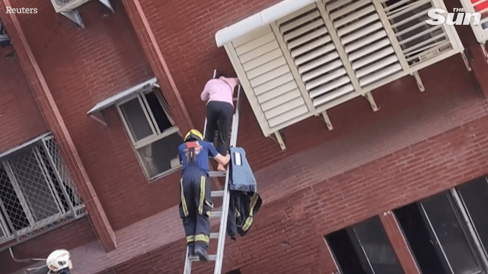 Emergency services rescue a woman from a damaged building