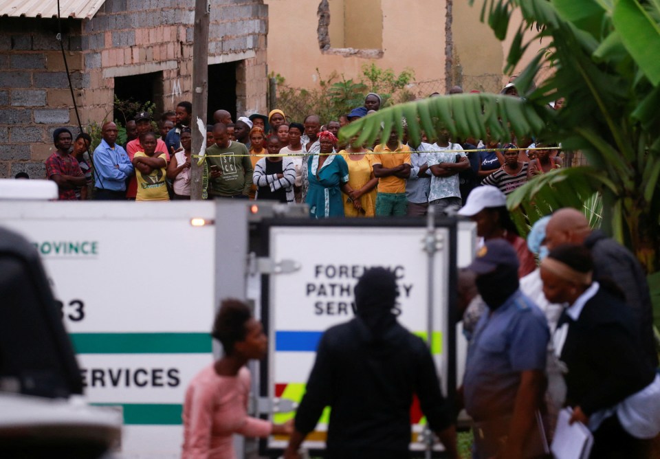 Neighbours look on as the bodies of suspected criminals killed during a police raid are identified by family members
