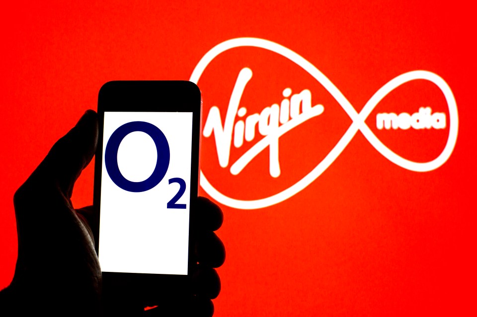 a person holding a cell phone in front of a virgin media logo