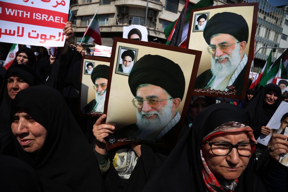 Veiled Iranian women carry portraits of the Iranian supreme leader Ayatollah Ali Khamenei