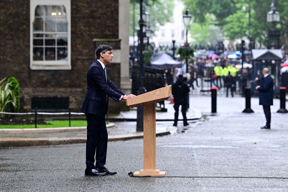 Sunak spoke as rain fell and he was drowned out by protest music
